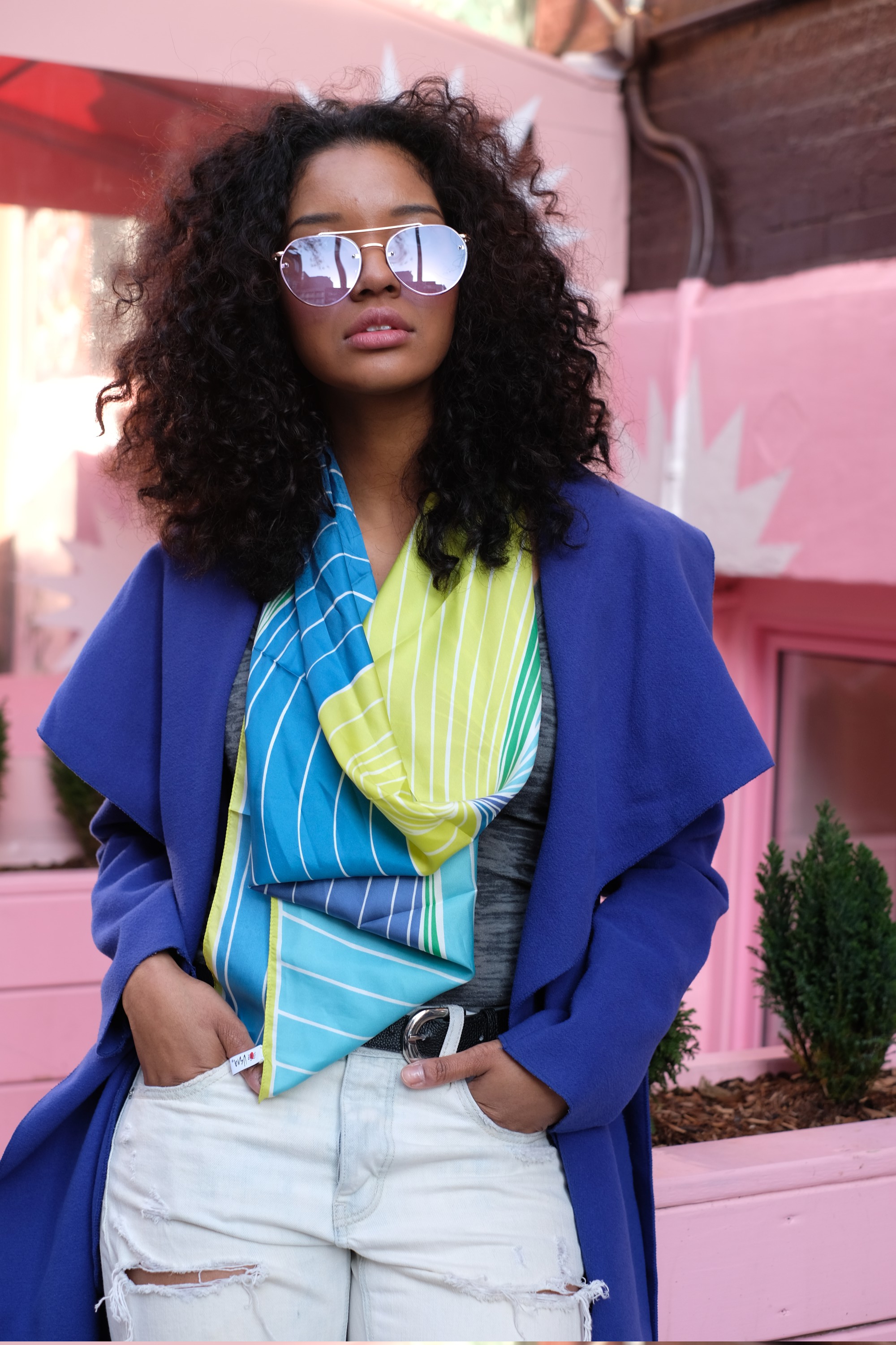 girl in blue coat by pink storefront