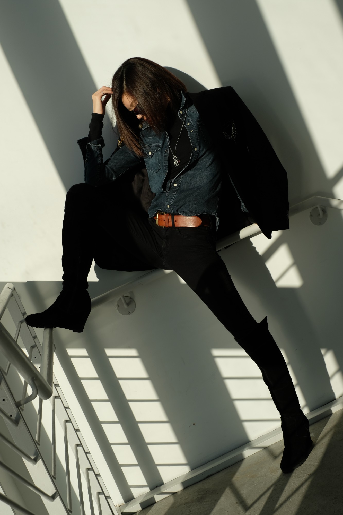 model in black outfit in shadowed stairwell