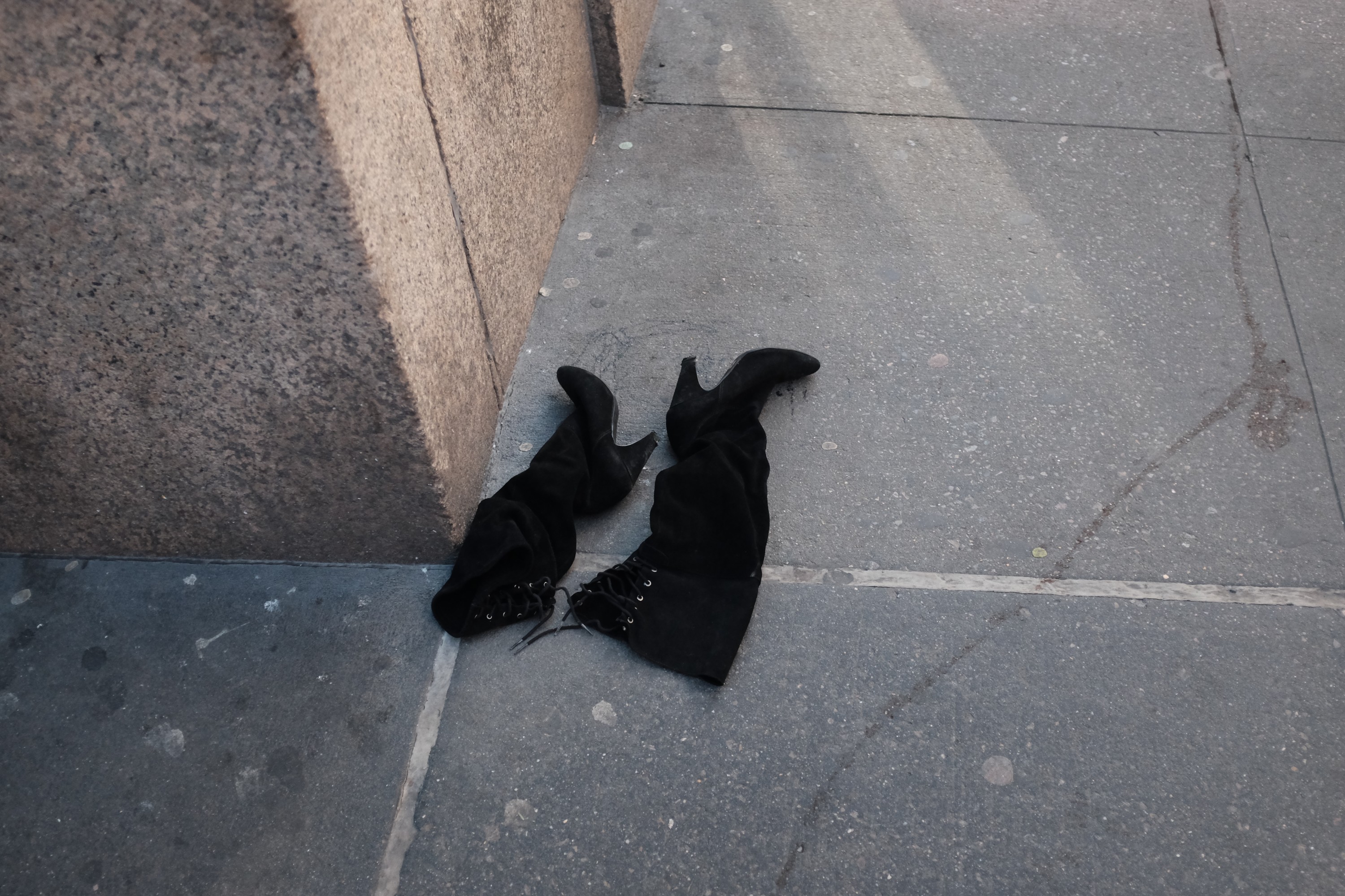 a pair of high black womens boots on the sidewalk