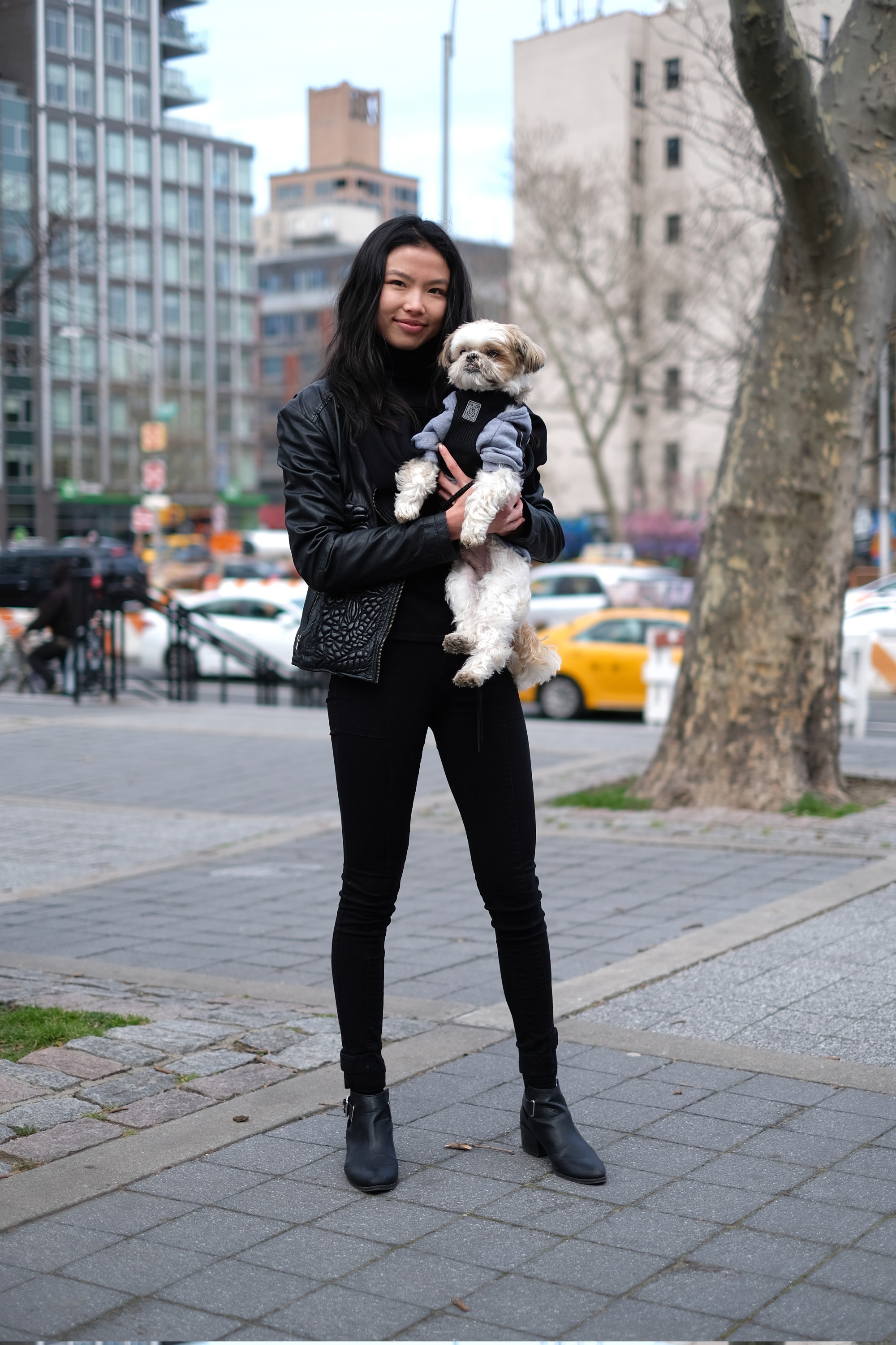 model in black outfit holding small dog