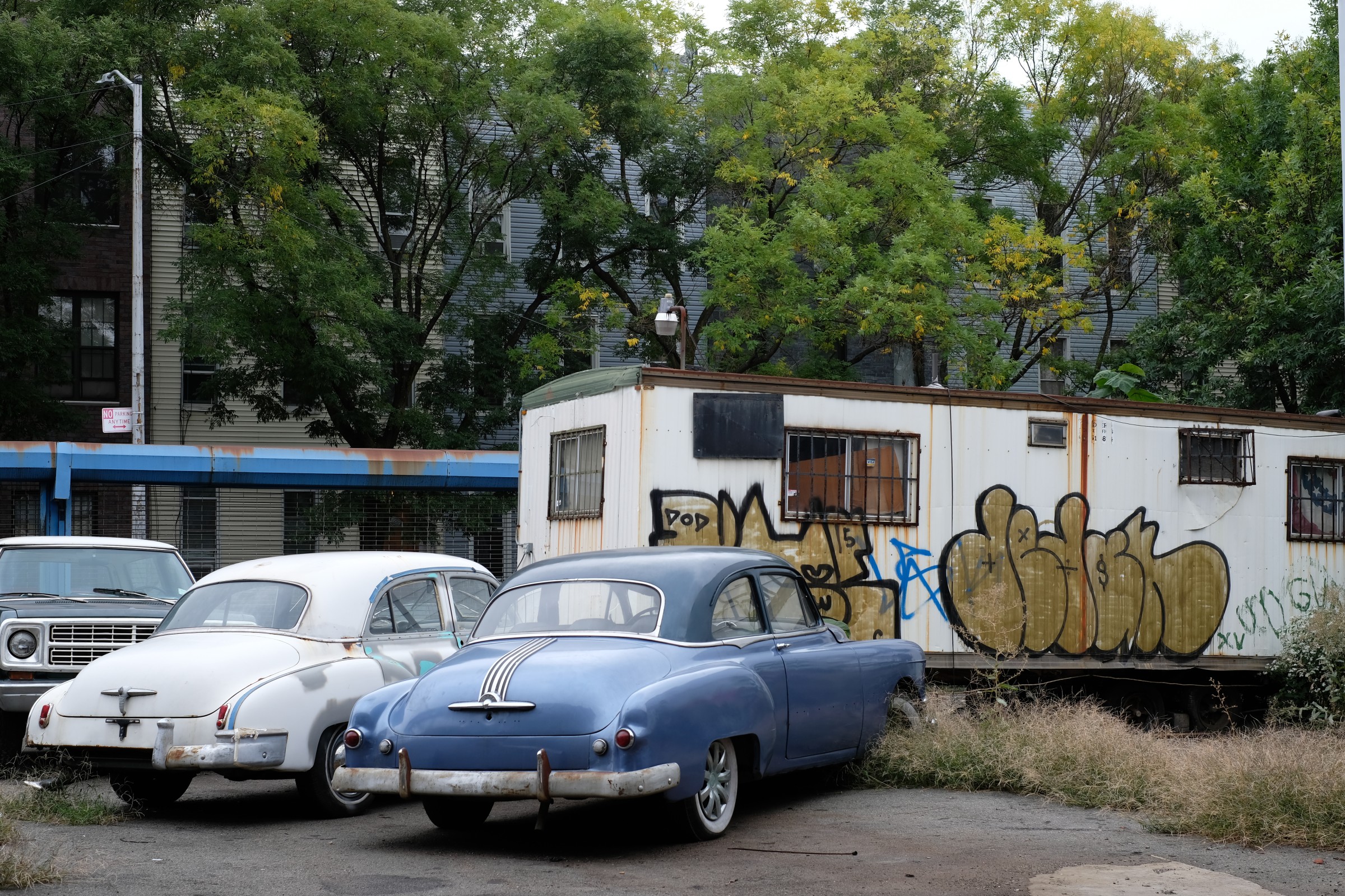 two abandoned 1950s cars and a trailer