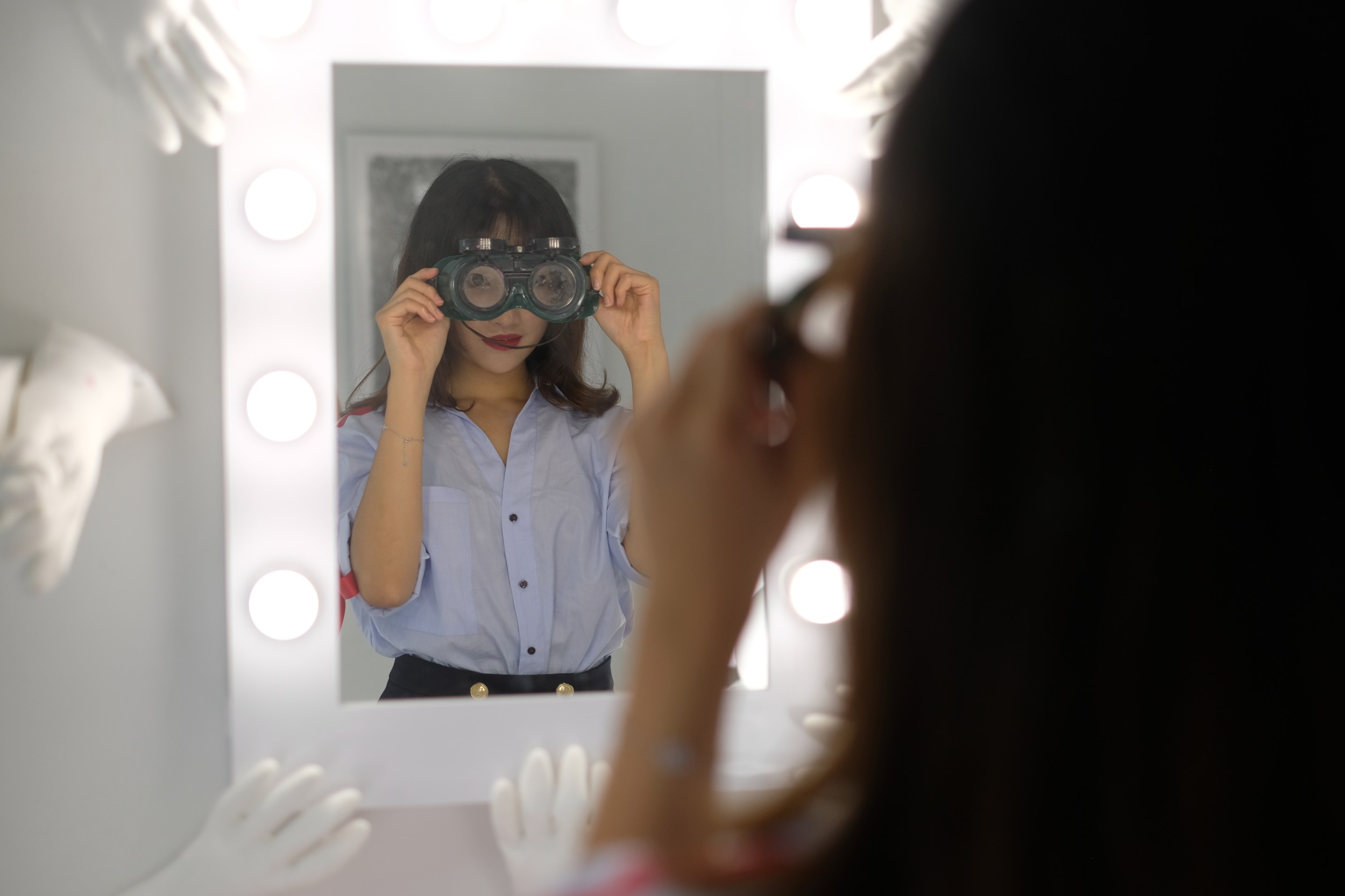 girl with goggles looking in mirror